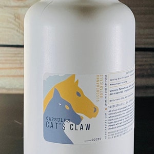 Puede incluir: Botella de plástico blanca con una etiqueta que dice "Capsules Cat's Claw" y presenta una ilustración amarilla y azul de una garra de gato. La etiqueta también incluye el nombre de la marca "Susquehanna Botanicals" e instrucciones para almacenar la botella en un lugar fresco y seco.
