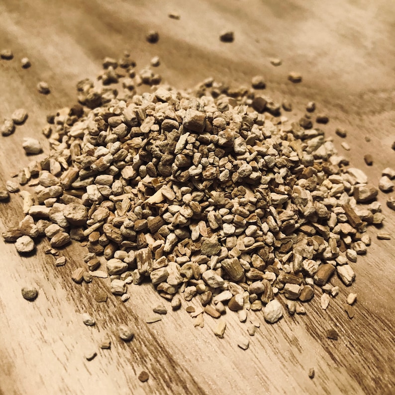 May include: A close-up of a pile of dried, light brown, irregularly shaped root pieces. The pieces are scattered on a light brown wooden surface.