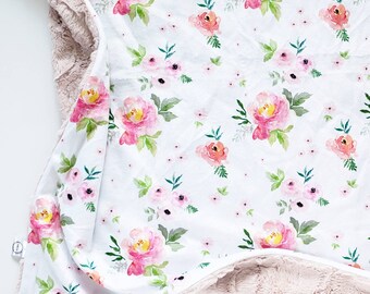 May include: A soft, plush blanket with a white cotton side featuring a pink floral pattern and a brown faux fur side. The floral pattern includes pink and white flowers with green leaves.
