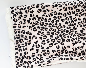 May include: A soft, plush blanket with a pink and black leopard print design. One side of the blanket is a soft, white faux fur.