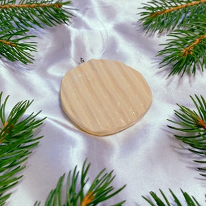 May include: A white, round, textured Christmas ornament with a string loop for hanging.