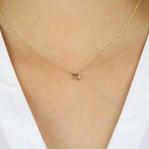 Puede incluir: Un collar de oro con un peque&ntilde;o y delicado colgante en forma del signo astrol&oacute;gico Virgo. El colgante tiene un peque&ntilde;o diamante en el centro.