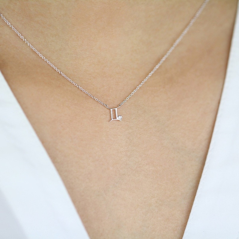 May include: A silver necklace with a Gemini zodiac symbol pendant and a small diamond accent.