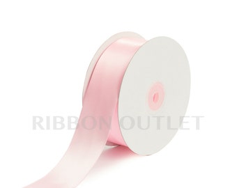 Pode incluir: Um carretel de fita de cetim rosa. A fita está enrolada em torno de um carretel de cartão branco. A fita é lisa e brilhante.