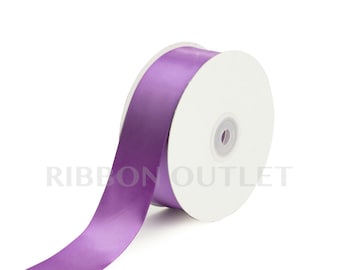 Pode incluir: Um rolo de fita de cetim roxo. A fita está em um carretel branco e está pronta para ser usada para artesanato, embrulho de presentes ou decoração.