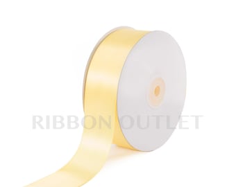 Pode incluir: Um rolo de fita de cetim amarelo canário. A fita está enrolada em torno de um carretel de cartão branco.