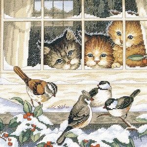 Puede incluir: Tres gatitos asoman por una ventana con nieve en el alféizar. Dos pájaros están posados en una rama con bayas rojas y hojas verdes. Un tercer pájaro está en una rama detrás de los gatitos.