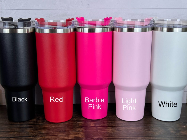 Op de afbeelding: Vijf roestvrijstalen bekers met deksels in verschillende kleuren: zwart, rood, felroze, lichtroze en wit. De bekers zijn gelabeld met hun kleuren.