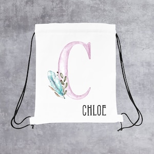 May include: White drawstring bag with a pink letter C and watercolor floral design. The bag has black drawstrings and the name Chloe is printed below the letter.