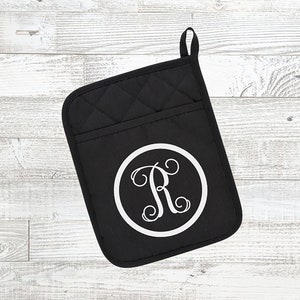 May include: Black quilted oven mitt with a white circle and the letter "R" in a script font.