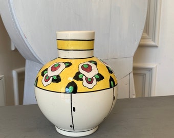 May include: A white ceramic vase with a yellow band and floral design. The vase has a round body and a narrow neck.