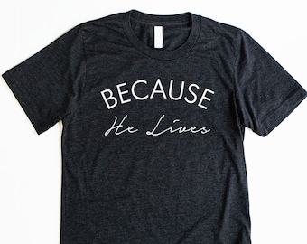 May include: A dark grey t-shirt with white text that reads "BECAUSE He Lives".