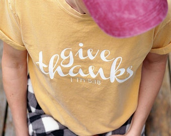 May include: A yellow t-shirt with the text "give thanks 1 Th 5:18" in white lettering.