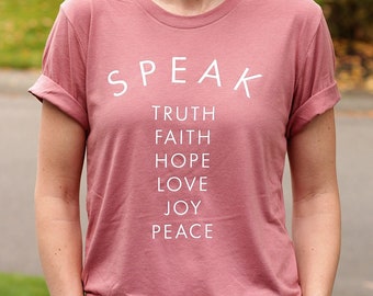 May include: A dusty rose t-shirt with the words "SPEAK TRUTH FAITH HOPE LOVE JOY PEACE" printed in white.