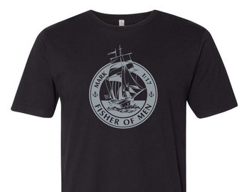 May include: Black crew neck t-shirt with a gray circular graphic. The graphic features a sailing ship with the text "MARK FISHER OF MEN 1:17" in a circular design. The shirt has a curved hemline.