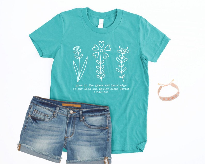 May include: Teal blue t-shirt with a white floral design and the text "grow in the grace and knowledge of our Lord and Savior Jesus Christ 2 Peter 3:10".