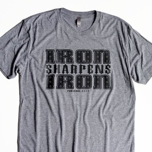 May include: A heather grey t-shirt with a black graphic that reads "IRON SHARPENS IRON" with the text "PROVERBS 27:17" below.