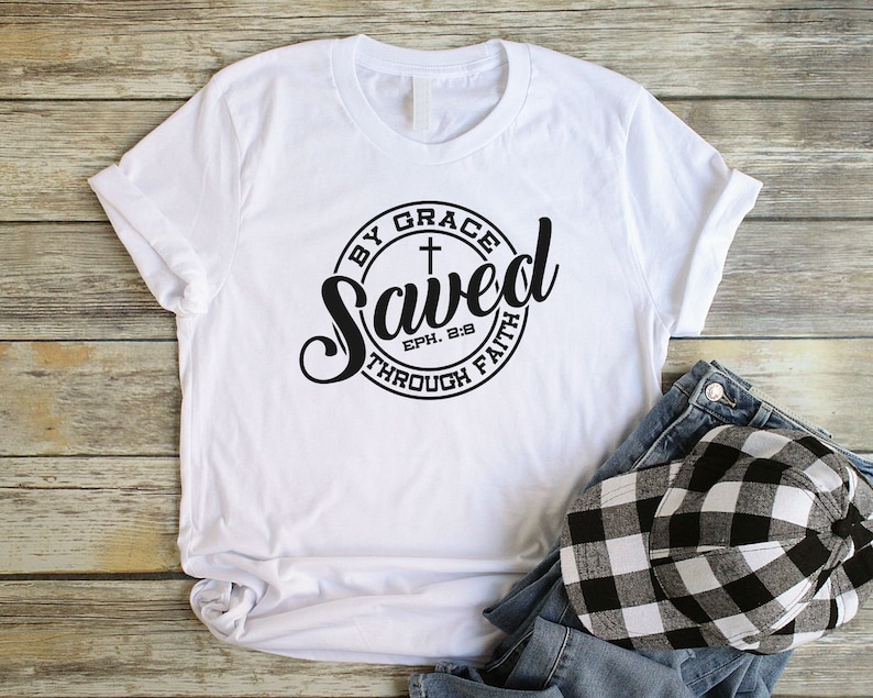 May include: White t-shirt with a black circle graphic that says "Saved by Grace through Faith" with a cross and the scripture reference "Eph. 2:8".