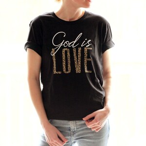 May include: A black t-shirt with the text "God is Love" printed in white with a leopard print pattern.
