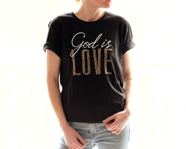 May include: A black t-shirt with the text "God is Love" printed in white with a leopard print pattern.