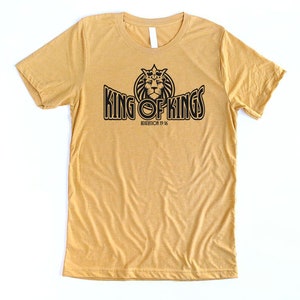 May include: A mustard yellow t-shirt with a black graphic of a lion wearing a crown and the text "KING OF KINGS" with the scripture reference "REVELATION 19:16".