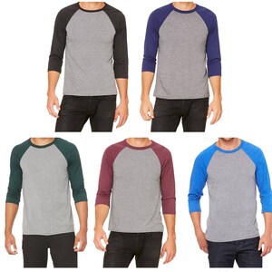 May include: Six different color variations of a grey triblend baseball t-shirt. The shirts feature a grey body with a contrasting color on the sleeves. The colors are: char black, navy, emerald, maroon, and royal.
