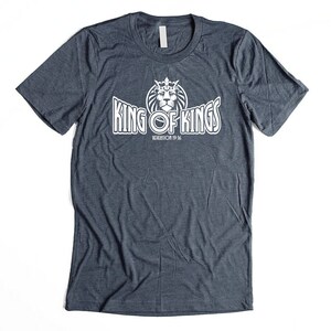 May include: A dark blue t-shirt with a white graphic of a lion wearing a crown and the text "King of Kings" with the words "Revelation 19:16" underneath.