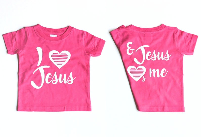 May include: Pink t-shirt with the text "I love Jesus" on the front and "& Jesus loves me" on the back. The text is in white with a white heart with stripes in the middle.