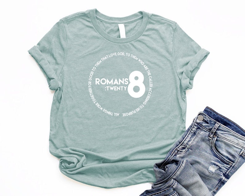 May include: A light blue t-shirt with a white circle graphic that says "Romans 8:Twenty" and "To His Purpose All Things Work Together For Good To Them That Love God, To Them Who Are The Called According To His Purpose".