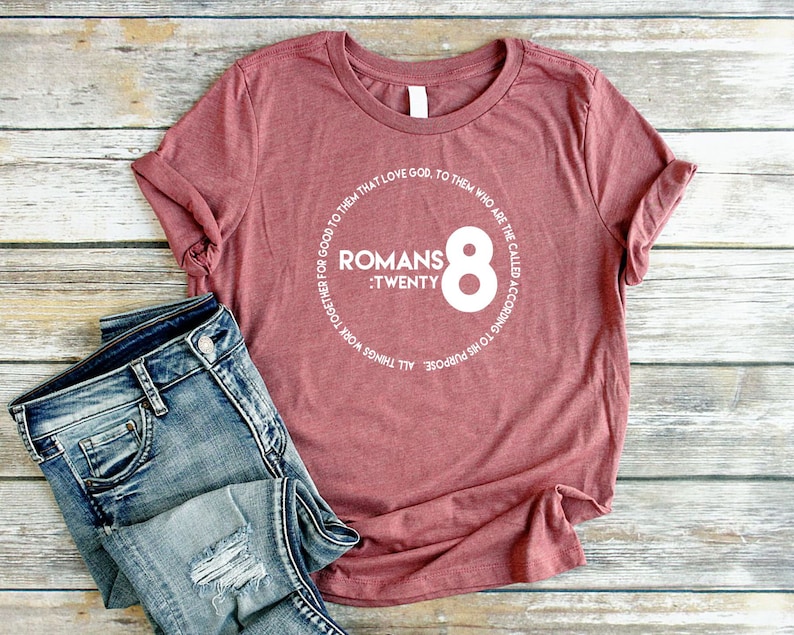 May include: A maroon t-shirt with a white circle graphic featuring the text "Romans :Twenty 8" and a white circle around the text.
