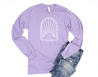 May include: A lavender long-sleeve t-shirt with a white graphic of a sunrise over mountains and the text "Blessed be His glorious name forever and let the whole earth be filled with His glory" and "Psalm 72:19".