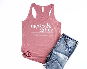May include: A dusty rose tank top with the text "mercy & grace" in white. The text below reads "not getting what we deserve & getting what we don't deserve."
