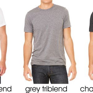 May include: Three men's t-shirts in different colors: solid white, grey, and charcoal black. All shirts are triblend.