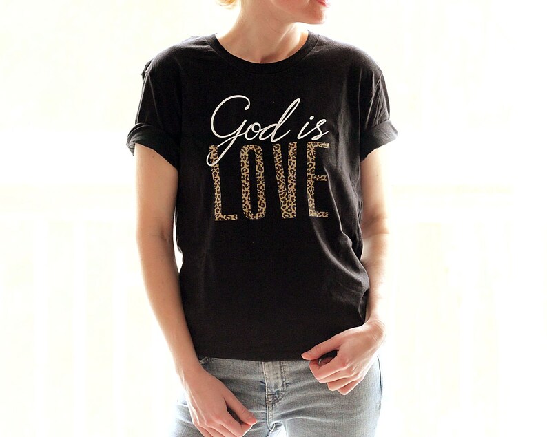 May include: Black t-shirt with the text "God is Love" in white lettering with a leopard print pattern.
