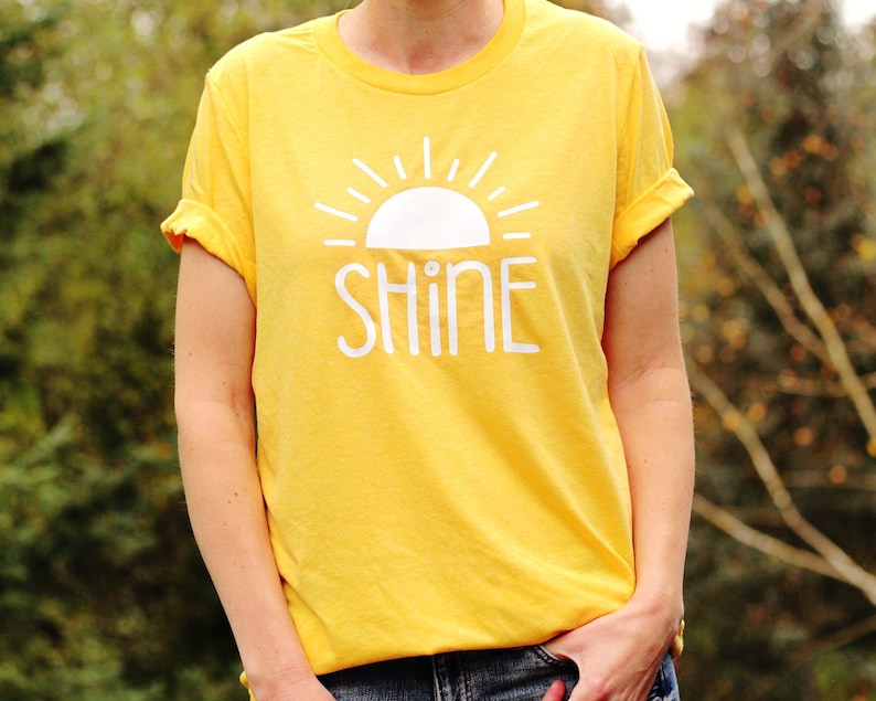 May include: A yellow t-shirt with a white sun and the word "SHINE" printed on the front.