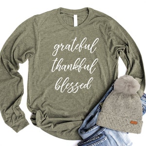 May include: A green long-sleeved t-shirt with the words "grateful thankful blessed" in white lettering.