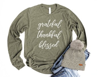 May include: A green long-sleeved t-shirt with the words "grateful thankful blessed" in white lettering.