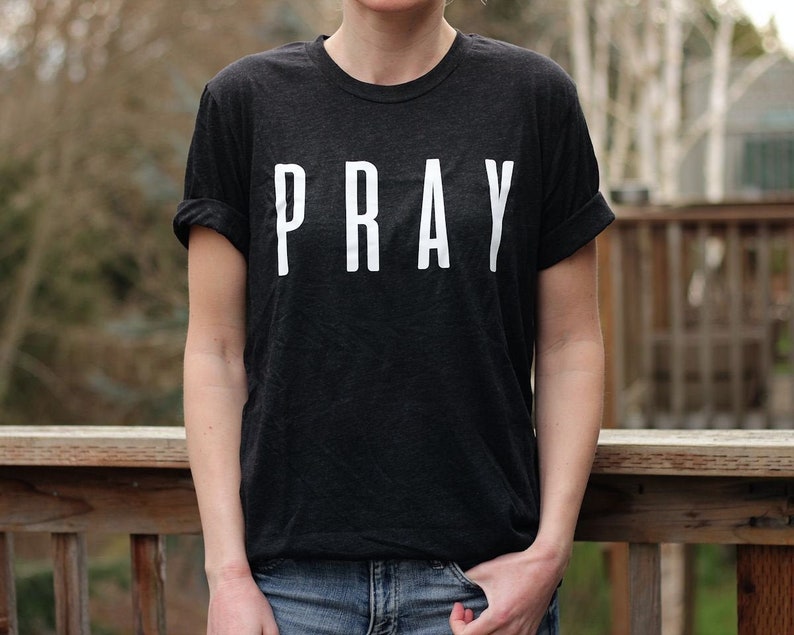 May include: A black t-shirt with the word "PRAY" printed in white on the front.