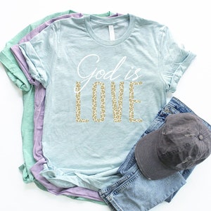 May include: A light blue t-shirt with the text "God is Love" in white lettering. The word "Love" is in a leopard print pattern.