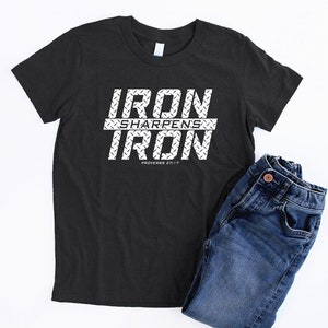May include: Black t-shirt with white text that reads "IRON SHARPENS IRON" with a diamond plate pattern behind the text. The text also includes "PROVERBS 27:17".