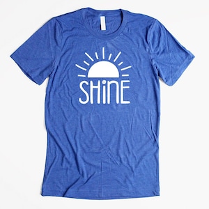 May include: A blue t-shirt with a white sun and the word "SHINE" printed on the front.