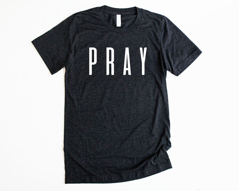 May include: A dark gray t-shirt with the word "PRAY" printed in white on the front.