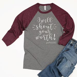 May include: A gray and burgundy raglan t-shirt with the text "I will shout your worth! Psalm 139:13" printed in white on the front.