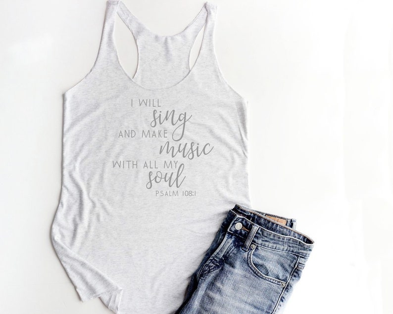 May include: A white tank top with the text "I will sing and make music with all my soul Psalm 108:1" printed on it. The tank top is paired with blue jeans.