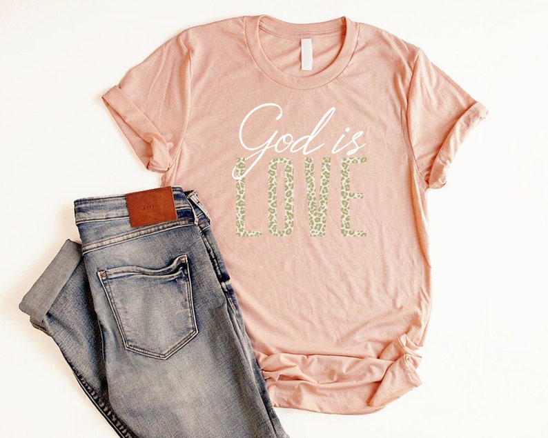 May include: A peach-colored t-shirt with the text "God is Love" in white lettering. The word "Love" is in a leopard print pattern.