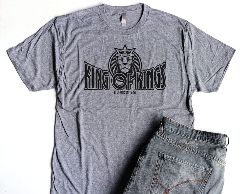 May include: A heather grey t-shirt with a black graphic of a crowned lion and the text "KING OF KINGS" with the scripture reference "REVELATION 19:16".