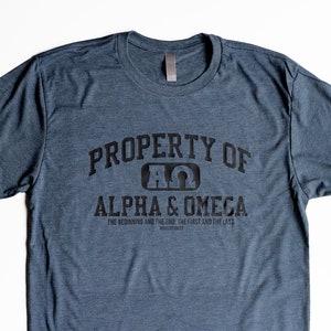 Pu&ograve; includere: Una maglietta blu scuro con il testo "PROPERTY OF A&Omega; ALPHA & OMEGA THE BEGINNING AND THE END. THE FIRST AND THE LAST REVELATION 22" stampato in nero.