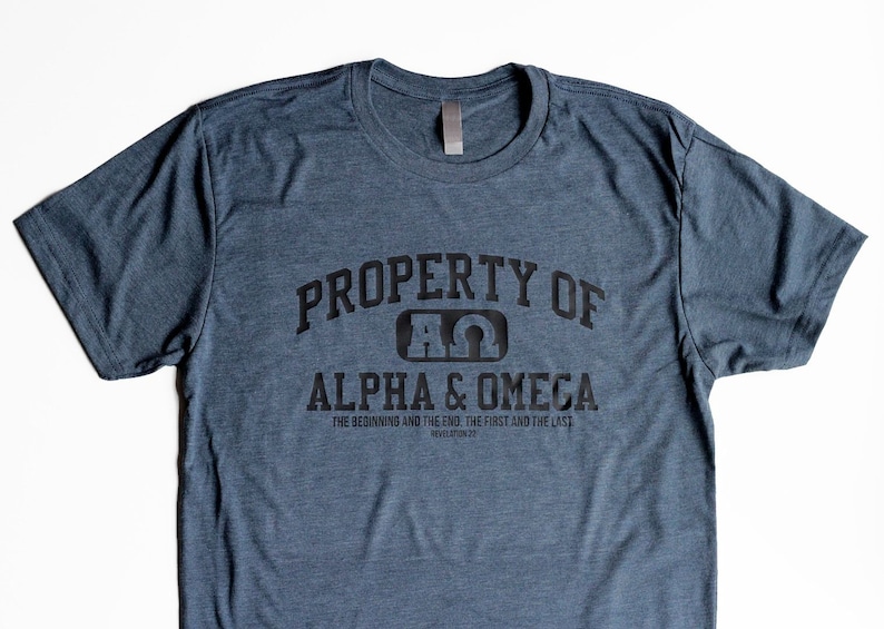 Pu&ograve; includere: Una maglietta blu scuro con il testo "PROPERTY OF A&Omega; ALPHA & OMEGA THE BEGINNING AND THE END. THE FIRST AND THE LAST REVELATION 22" stampato in nero.