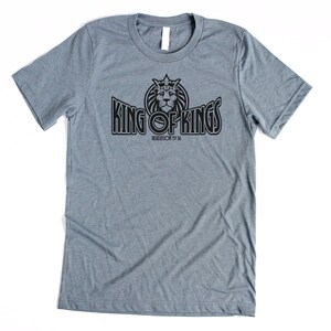 May include: A heather gray t-shirt with a black graphic of a lion wearing a crown and the text "King of Kings" with the scripture reference "Revelation 19:16".