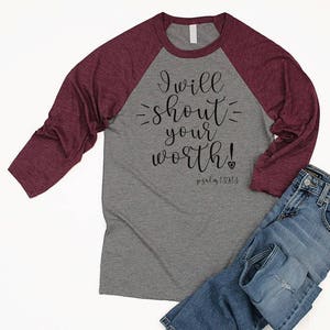 May include: A gray and burgundy raglan t-shirt with the text "I will shout your worth! Psalm 139:13" printed on the front.